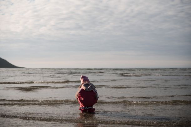 Foto av jente fra familiefoto som ser utover havet